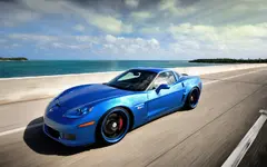 blue_corvette_driving_by_the_sea_1280x800.webp